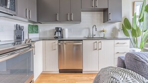 Une cuisine moderne avec des meubles gris, des appareils électroménagers en acier inoxydable et un lave-vaisselle.