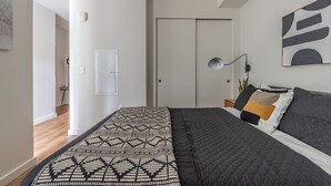 Une chambre à coucher avec un lit, une table de chevet, une lampe et une porte.