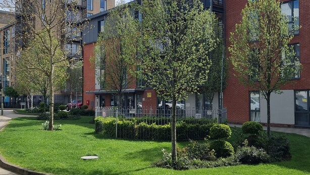 A modern building with a brick facade, surrounded by well-maintained grass and trees.