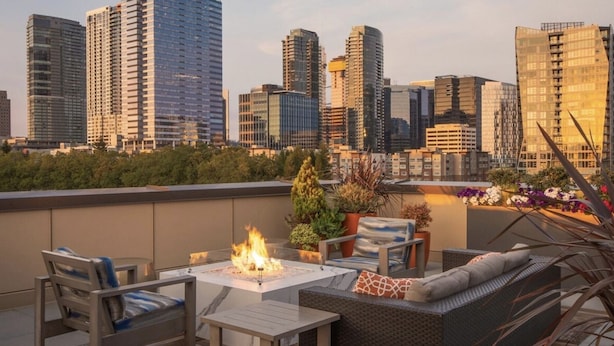 A rooftop terrace with a fire feature, seating, and a city skyline view. - 1BR | Gym, Views | Bellevue | Sophari Parkside A (Bellevue)