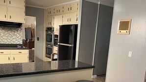 A kitchen with a central island, bar stools, a built-in oven, and a refrigerator. - Beautiful large home on Lake Chickamauga at Dallas Bay with private boat ramp. (Middle Valley)