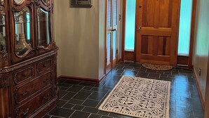 A hallway with a wooden door, a chandelier, and a large wooden cabinet. - Beautiful large home on Lake Chickamauga at Dallas Bay with private boat ramp. (Middle Valley)