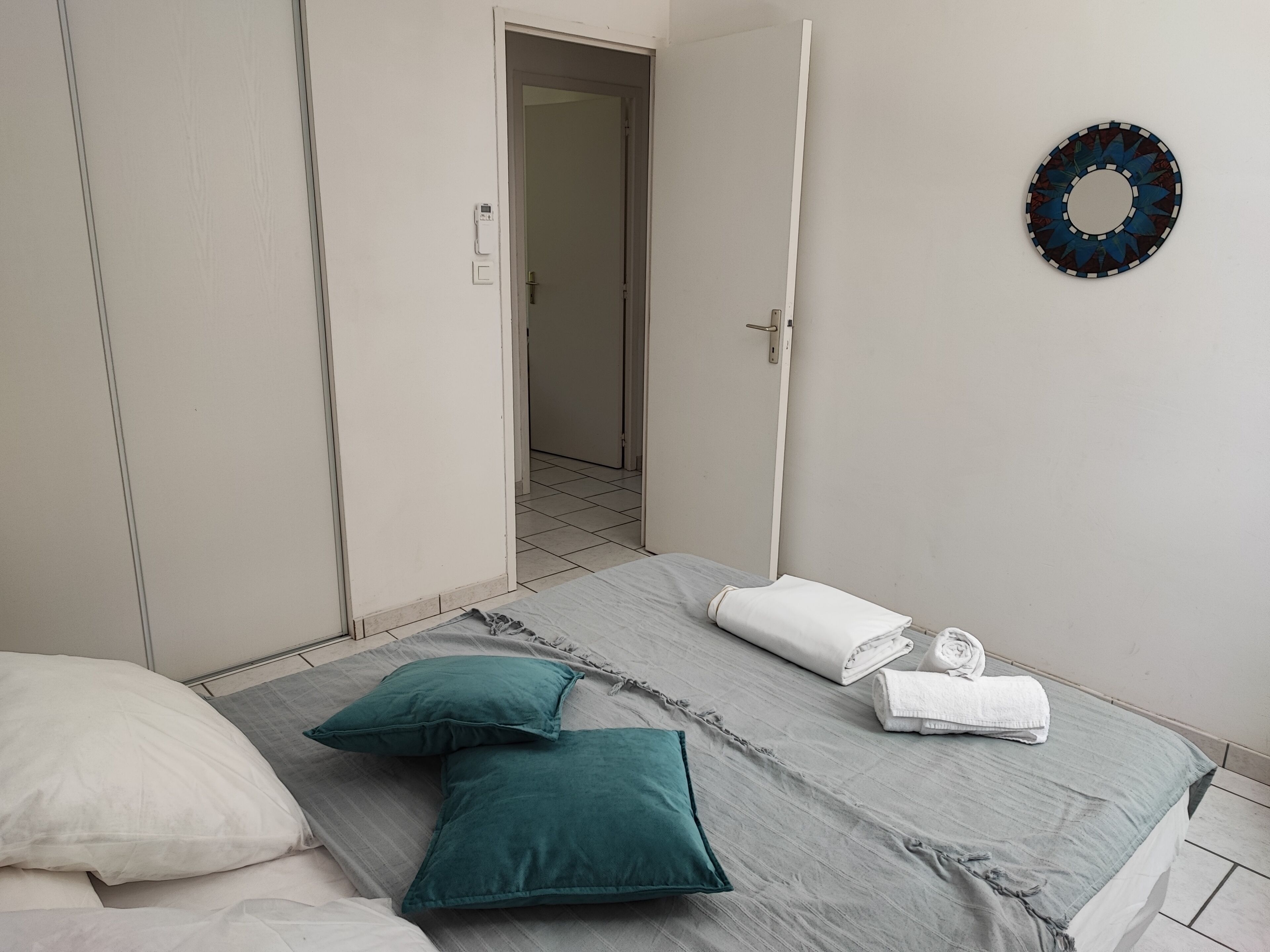 Une chambre à coucher avec un lit, des oreillers, une serviette, une porte et un élément de décoration murale.