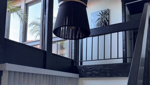 A modern interior with a staircase, a black pendant light, and a view of the outside.