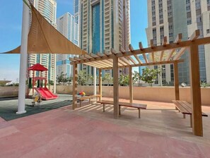 Relax in a serene outdoor space with a shaded seating area and a children's play structure nearby.