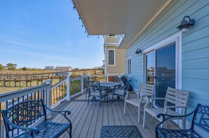 Eine überdachte Terrasse mit Tisch, Stühlen, einer Bank und einem Geländer.