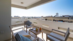 A rooftop terrace with a clear view of the cityscape, featuring a table with chairs and a small table with a glass jar of fruit. - Zest City Residence by Nomads (Paphos)