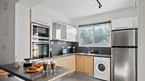 Eine moderne Küche mit Einbauofen, Mikrowelle, Kaffeemaschine und Geschirrspüler.