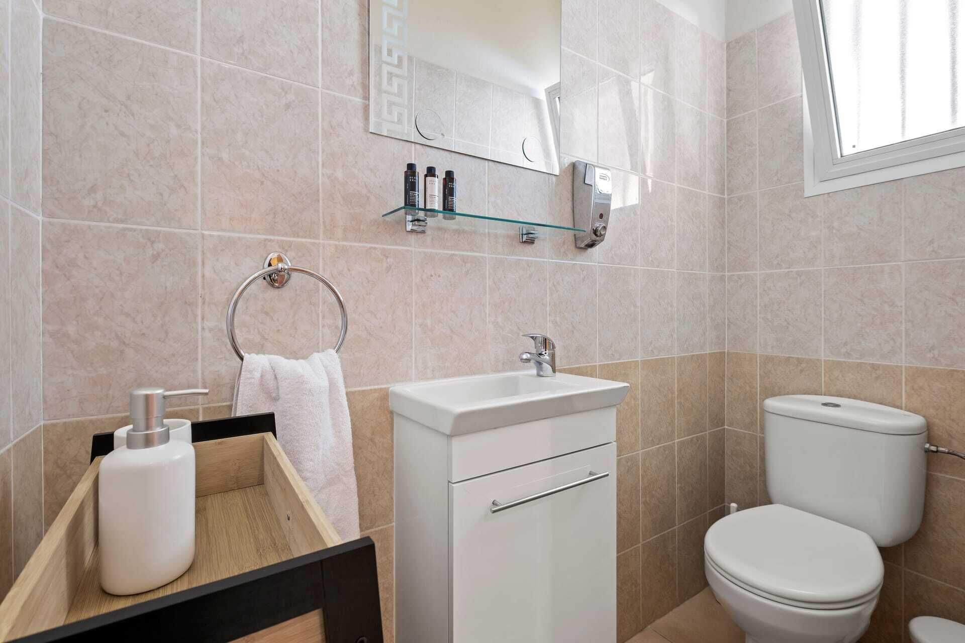 A modern bathroom with a sink, mirror, and toilet.