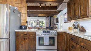 A kitchen with wooden cabinets, a stainless steel refrigerator, and a built-in oven.
