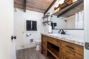 A bathroom with a wooden vanity, a large mirror, and a white sink.