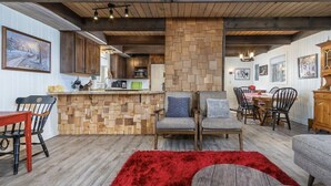A cozy interior with wooden flooring, a red rug, and a dining area with chairs and a table.