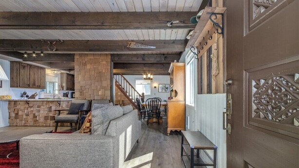 A spacious living area with a large grey sofa, a wooden coffee table, and a red rug. A staircase leads to an upper level with a wooden railing.