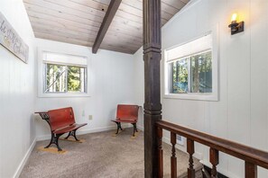 A room with two wooden benches, a wooden staircase, and a window with a view of trees.