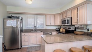 A kitchen with a stainless steel refrigerator, a microwave, a stove, and a sink. There are wooden cabinets and a granite countertop. - 8280 The peak- Hot tub, ski in/ ski out, Pool table, Golf course, fire pit (Clymer)