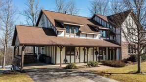 A two-story house with a covered porch, a chimney, and a large window. - 8280 The peak- Hot tub, ski in/ ski out, Pool table, Golf course, fire pit (Clymer)