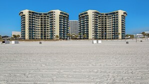 Ein großes, mehrstöckiges Hotel mit einer symmetrischen Fassade, direkt an einem Sandstrand gelegen.