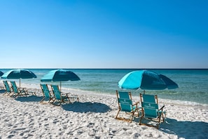 A beach with rows of wooden beach chairs and blue umbrellas labeled 'Edgewater'.