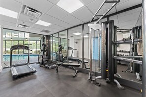 A gym with exercise equipment, a treadmill, and a view of a swimming pool. - Terrace Suite with Epic Fireworks View (Orlando)