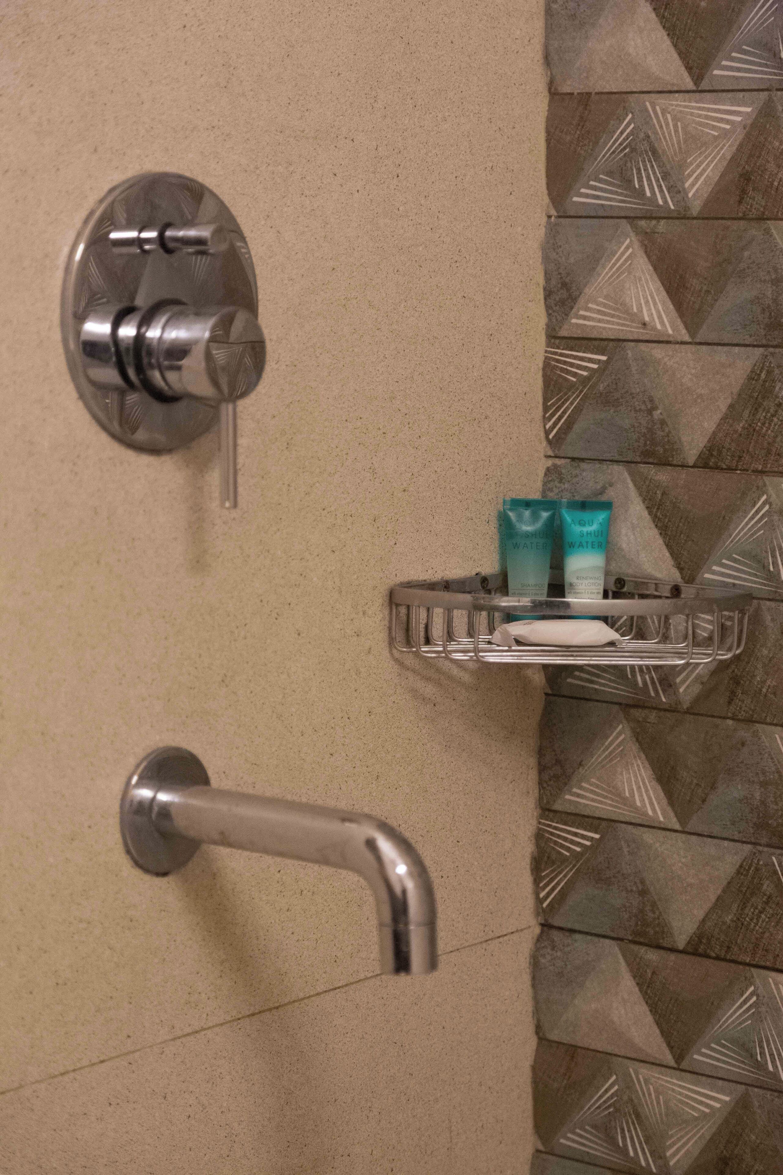A bathroom with a shower, a towel rack, and a soap dispenser.
