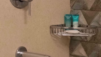 A bathroom with a shower, a towel rack, and a soap dispenser.