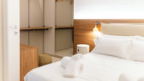 A hotel room with a neatly made bed, a wooden wardrobe, a bedside table, and a wall-mounted light. - Moments by Monholiday (Monopoli)