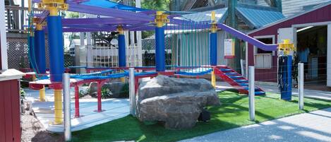 Un parque infantil con estructuras para escalar y una formación rocosa.