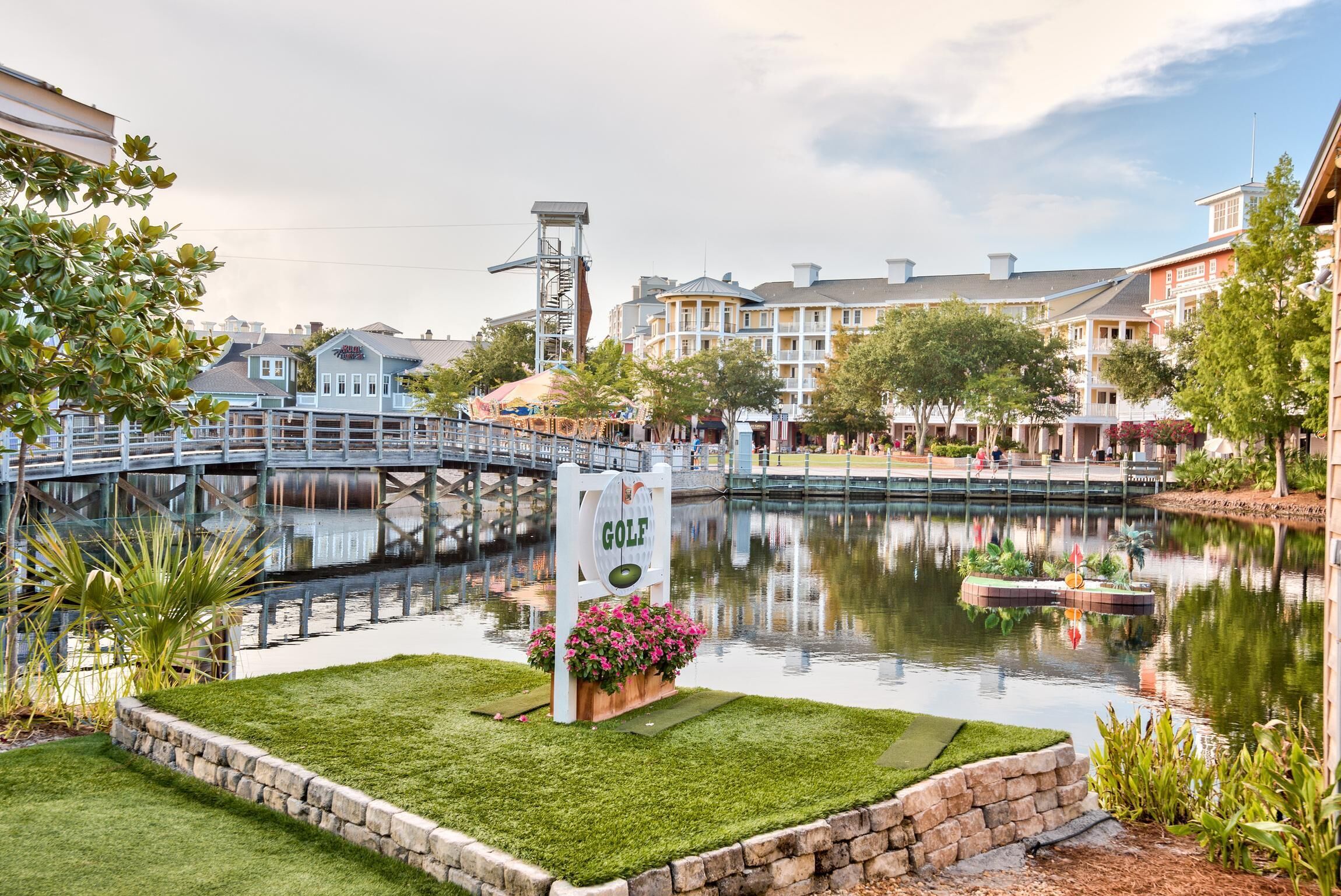 A golf sign, a bridge, and buildings in the background.