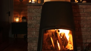 A wood-burning stove in a room with wooden floors and a brick wall.