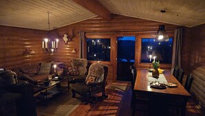 A cozy log cabin interior with a dining area, a sofa, and a fireplace.