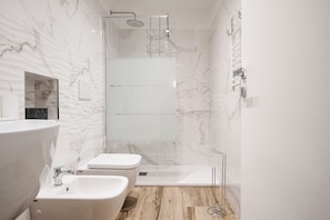 A modern bathroom with a glass-enclosed shower, a large white sink, and a toilet.
