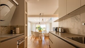 A modern kitchen with a dining area, wooden flooring, and a view of greenery outside. - Villa Oleander Zadarvillas (Zadar)