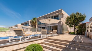 A modern building with a pool, outdoor seating, and steps leading to a balcony. - Villa Oleander Zadarvillas (Zadar)