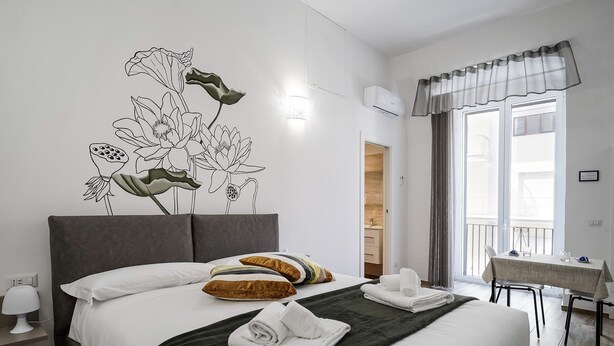 Ein Hotelzimmer mit einem großen Bett, einer Wandmalerei, einem Essbereich und einem Balkon.