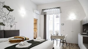 Ein modernes Hotelzimmer mit einem großen Bett, einem Esstisch und einer Küchenzeile.