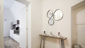 Ein modernes Interieur mit Holzboden, weißer Wand und einem kleinen Tisch mit dekorativen Gegenständen.