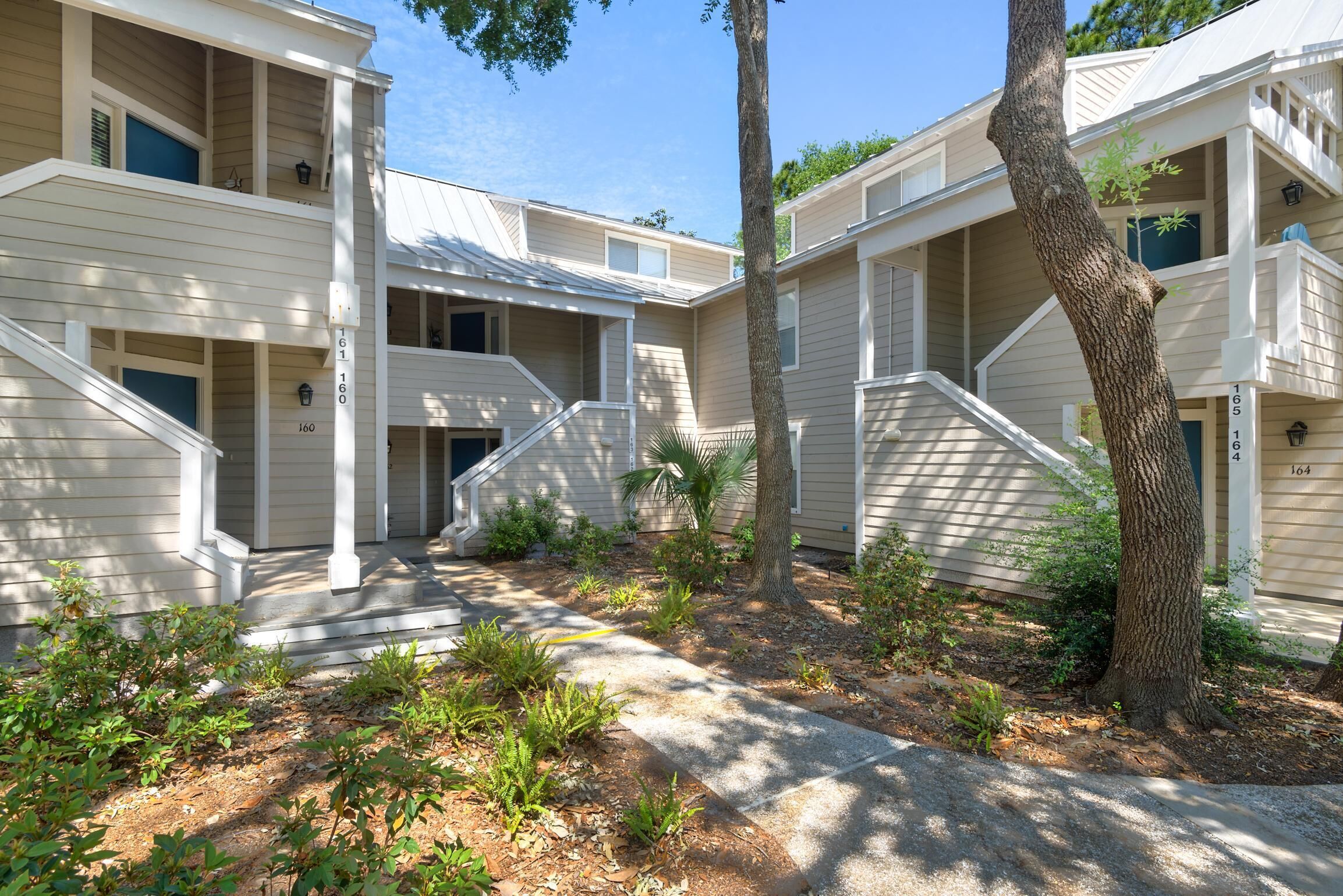 A residential building with multiple units, each featuring a balcony and a small porch area.