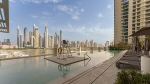 Una piscina infinita en la azotea con vistas al horizonte urbano, sillas de descanso y un flotador salvavidas.