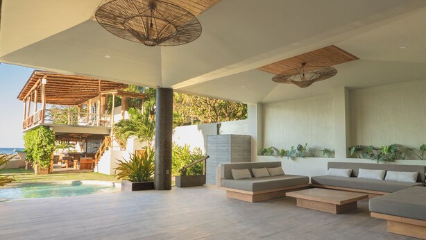 A modern outdoor living area with a pool, wooden deck, and seating. - Mirasurf Hotel & Waves (Tamanique)