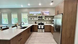 Une cuisine moderne dotée d’un îlot central, d’appareils électroménagers en acier inoxydable et de meubles de rangement en bois.
