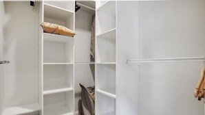 A white closet with multiple shelves and a hanging rod. - Prosper Point Home with BBQ, Patio and Parking (Auckland West)