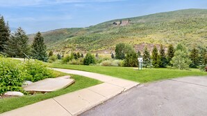 Un sendero pavimentado que conduce a una zona verde con vistas a una colina y árboles.