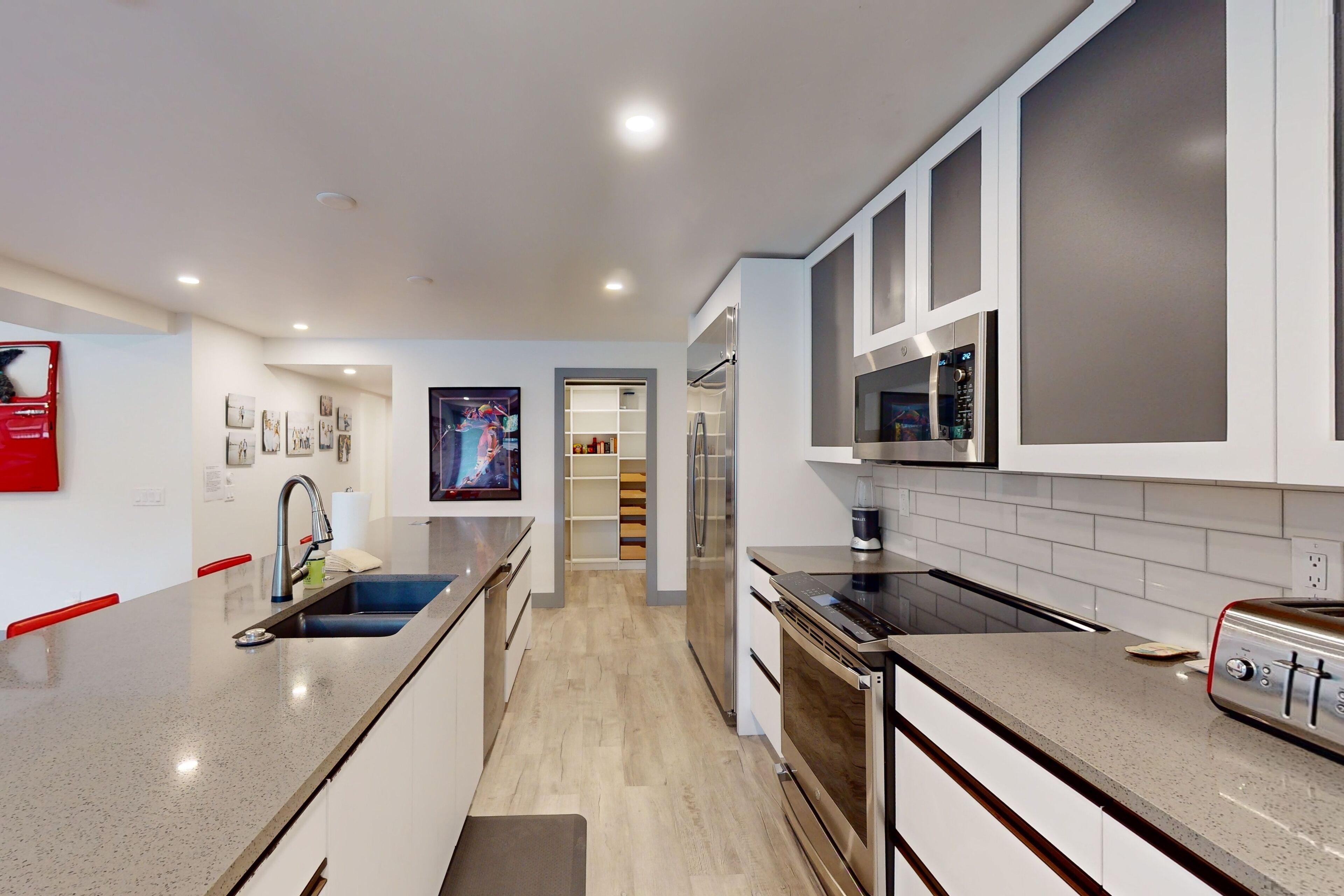 A modern kitchen with a central island, stainless steel appliances, and a walk-in pantry.