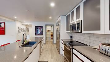 A modern kitchen with a central island, stainless steel appliances, and a walk-in pantry.