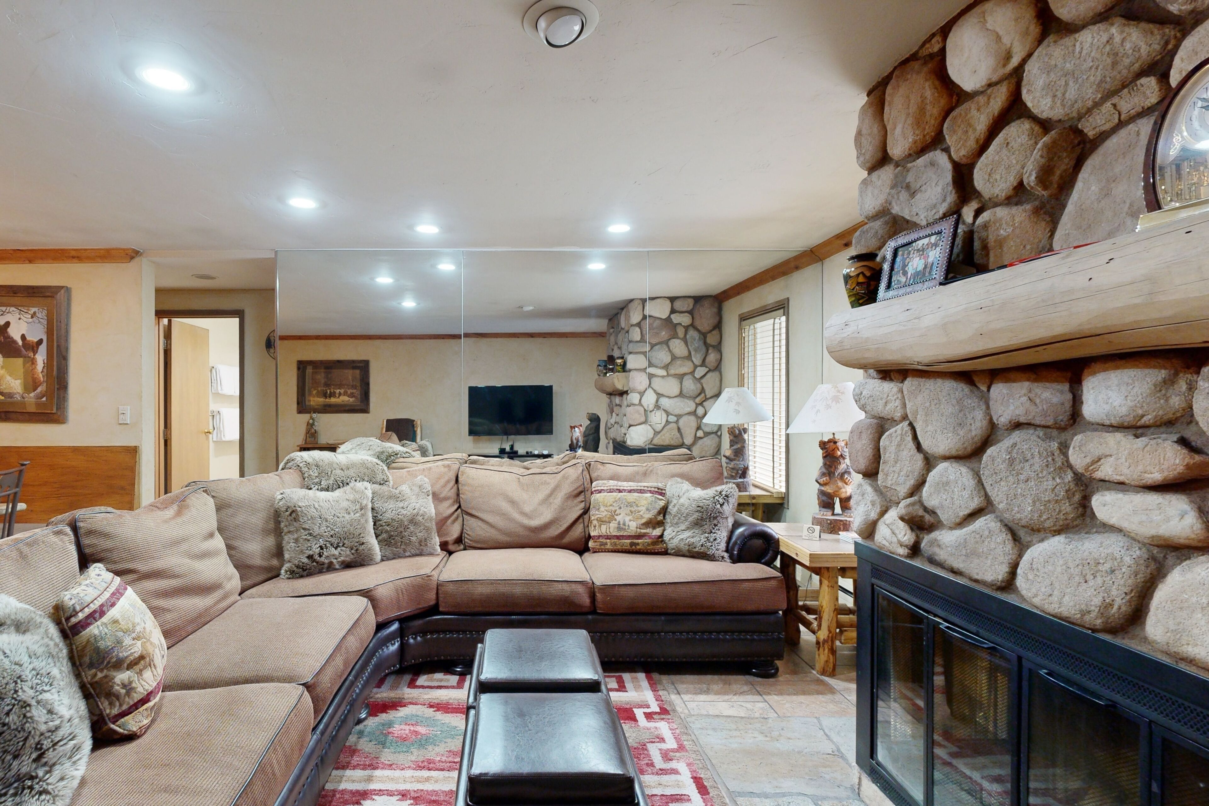 A living room with a sectional sofa, a fireplace, and a stone accent wall.