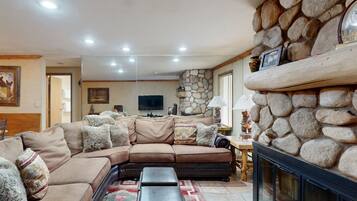 A living room with a sectional sofa, a fireplace, and a stone accent wall.