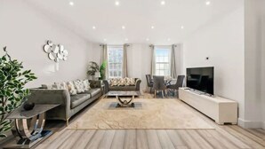 Un salon moderne avec un canapé, une table basse, un téléviseur et une plante.
