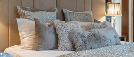 A neatly made bed with a patterned bedspread and multiple pillows, including a fluffy one.