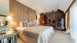Une chambre à coucher moderne avec un grand lit, une tête de lit en bois, une table de chevet et une armoire.