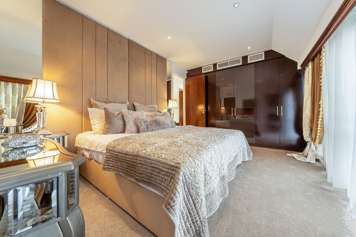 Ein modernes Schlafzimmer mit einem großen Bett, einem Holz-Kopfteil, einem Nachttisch und einem Kleiderschrank.